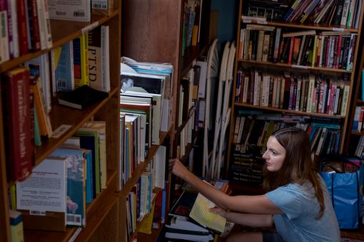 Women places book on a library shelf